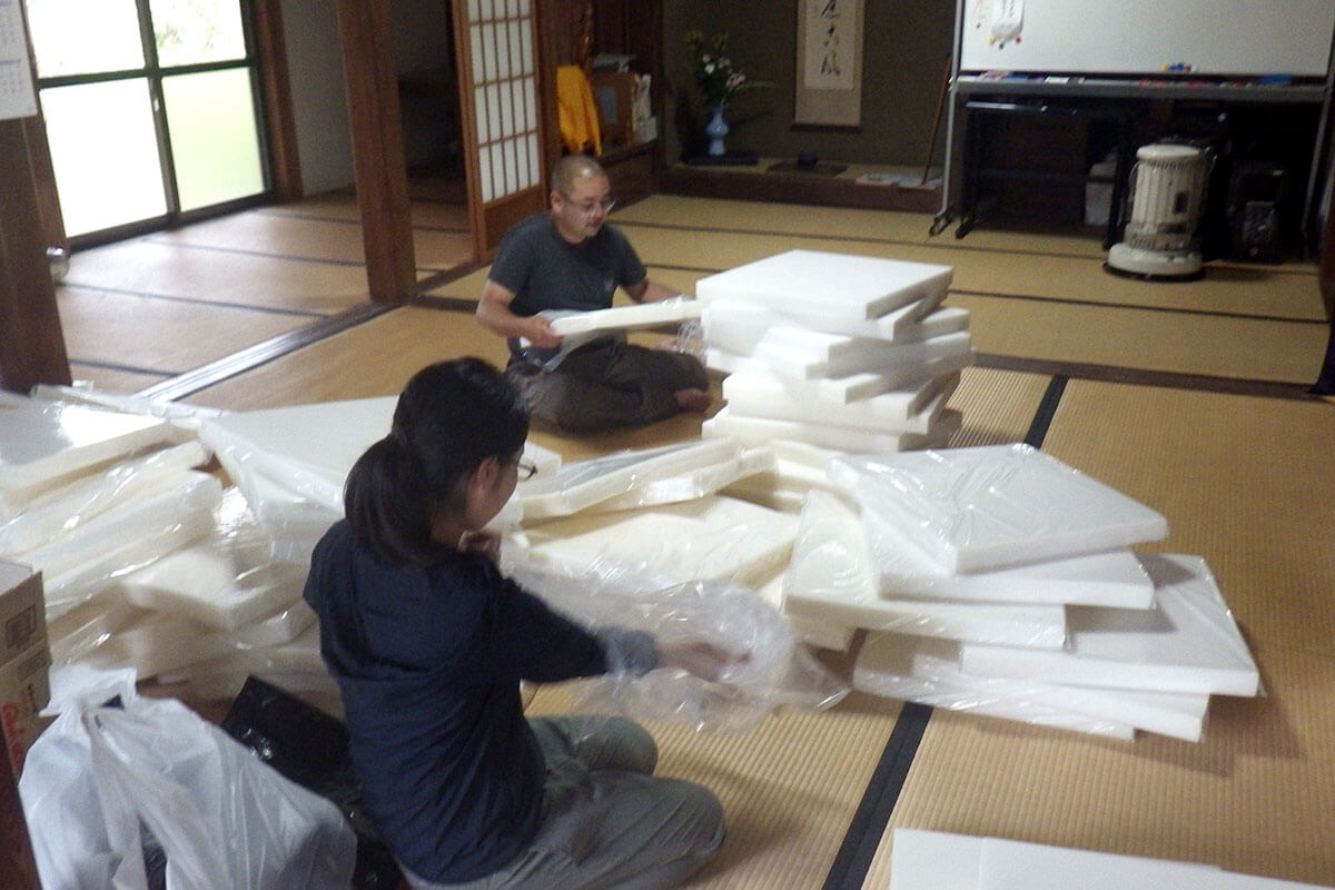 お寺の本堂で座布団を詰める作業の様子