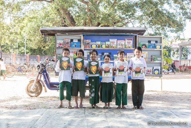 ミャンマーの移動図書館バイクの前で記念撮影する子どもたち