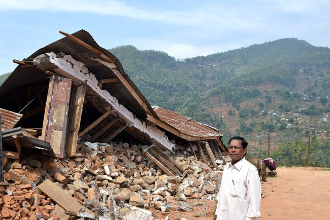 2015年のネパール大地震で倒壊した校舎の前に立つ校長先生