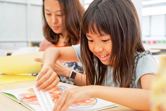 アジアの子どもに届ける絵本に親子で翻訳シールを貼っている様子