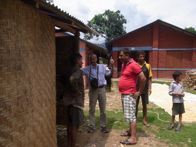 村の人たちに学校の状況を尋ねるNSETスタッフ（左から2番目）