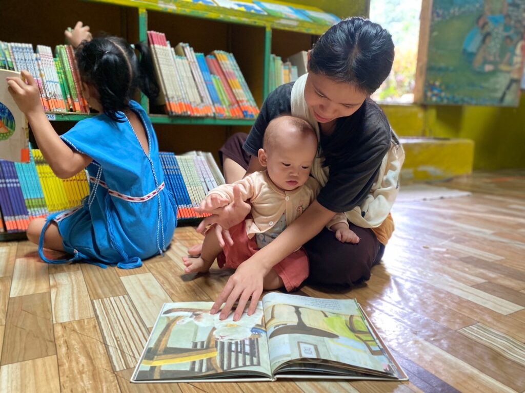 A mother with her kid enjoy looking at the picture; a bright picture will catch a small kid's attention