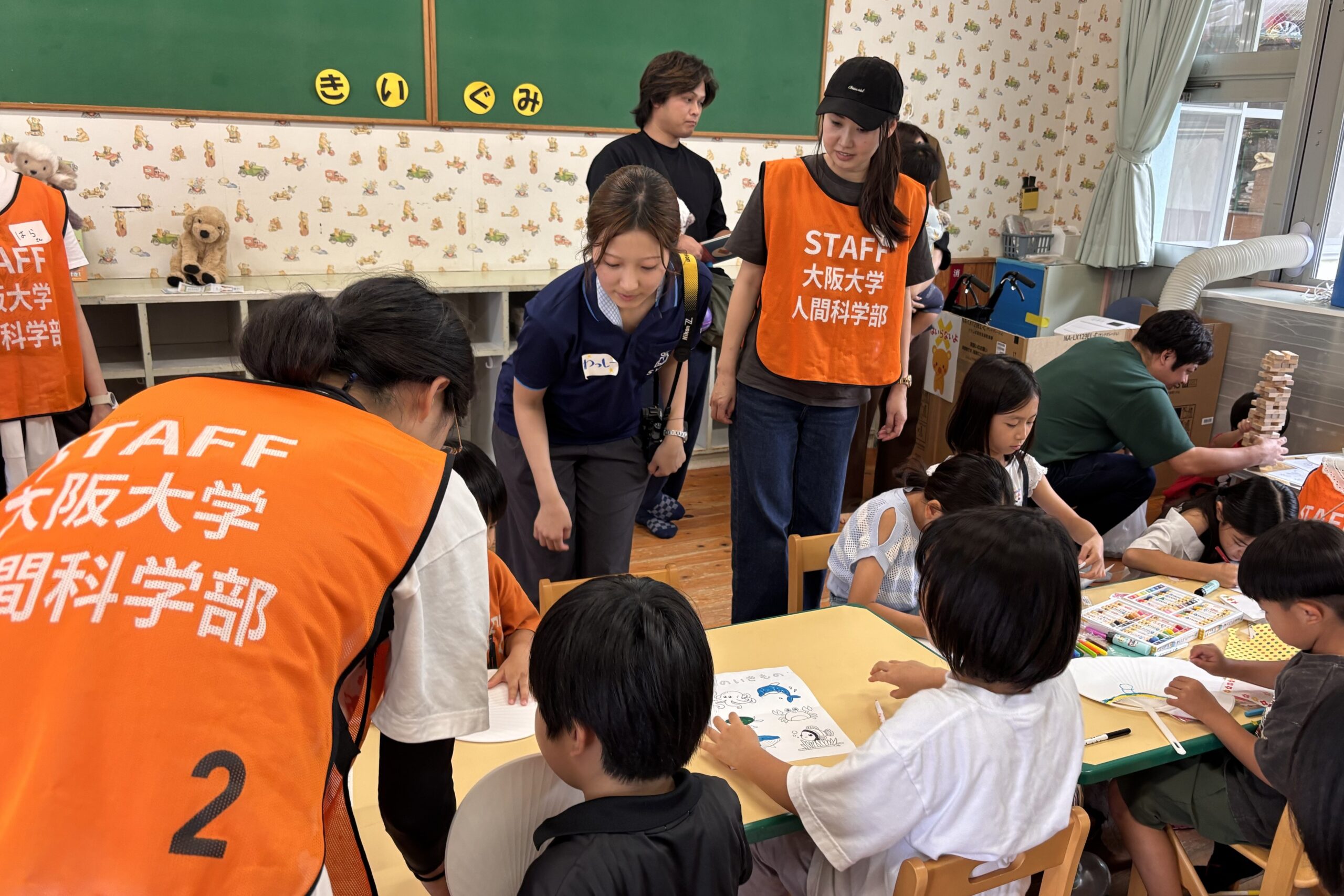 じゆうあそびコーナーで、塗り絵をしている子どもたちと、それを見ているシャンティのスタッフと大阪大学の学生