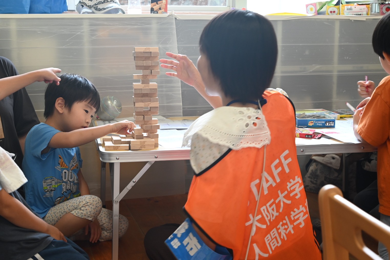 大阪大学の学生ボランティアが子どもとジェンガで遊んでいる